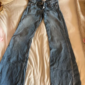 Blå low waist bootcut jeans från Gina Tricot - Säljer ett par blå low waist bootcut jeans från Gina Tricot. Jeansen har klassisk femficksdesign, tre knappar framtill samt vida ben.
