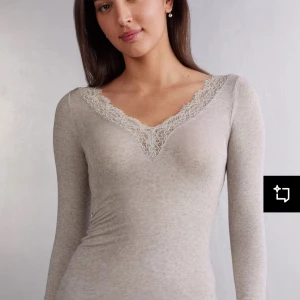 Beige intimissmi tröja  - Säljer en beige långärmad topp med v-ringning och fin spetsdetalj runt halsen. Toppen är figurnära och passar perfekt till lager-på-lager eller som den är. Supermjuk och stretchig i materialet. Den är från intimissmi.