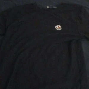 Svart tröja från Moncler - Säljer en svart långärmad tröja från Moncler med rund halsringning och klassisk logotyp på bröstet. Enkel och stilren design som passar till mycket.
