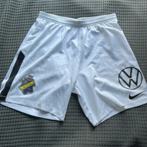 Vita AIK fotbollsshorts från Nike - Säljer ett par vita AIK fotbollsshorts från Nike med svart sidopanel, AIK-logga och Volkswagen-logga framtill. Shortsen är tillverkade i lätt polyester med Dri-FIT-teknologi och har resår i midjan.