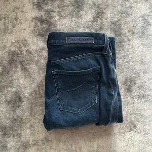 Mörkblå jeans från Jacob Cohën - Snygga mörkblå jeans från Jacob Cohën med klassisk femficksdesign och raka ben. Jeansen har en diskret logotyp på bakfickan och är tillverkade i ett mjukt denimtyg med stretch för extra komfort.