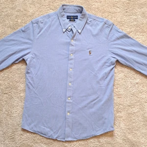 Ljusblå Ralph Lauren skjorta - Stl M Slim fit - Hej säljer en snygg Ralph Lauren skjorta I färgen ljusblå. Perfekt till sommaren! 🏖🏝 Skick: 8,5/10 bara en litet hål på vänster ärmen. Knappt något som syns vid användning. Modell: Slim fit. Storleken är ursprungligen en M. Bara att nån har klippt bort den biten där storleken stod. Hör av dig om du har några frågor. Mvh Galgen 🤗