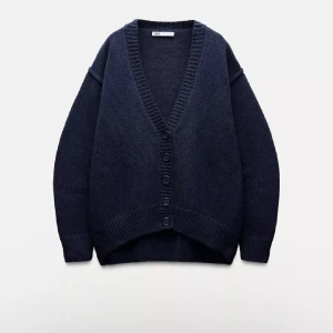 Mörkblå kofta från Zara - Mysig mörkblå kofta från Zara med v-ringning och stora knappar framtill. Koftan har lång ärm och ribbade muddar vid ärmslut och nederkant. Perfekt för lager-på-lager och enkel att styla till olika outfits.