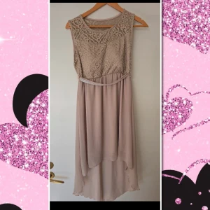 Beige långklänning med spets och strassbälte - Säljer en elegant beige långklänning med vacker spets upptill och ett glittrande strassbälte i midjan. Klänningen är ärmlös och har en mjuk, flowy kjol i polyester. Perfekt för festliga tillfällen! Har en liten tråd utdragen se sista bilden,  stl lapp bortklippt men passar mig som har stl S och 80D i bh. Till knäna fram och bak något längre 