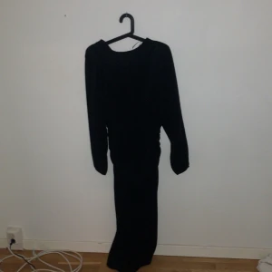 Svart glittrig långklänning från Gina Tricot - Säljer en svart långklänning från Gina Tricot med glittrigt tyg. Klänningen har långa ärmar och en rund halsringning. Perfekt för dig som vill sticka ut med en elegant look.