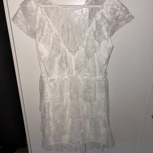 Vit spetsklänning från Bubbleroom - Säljer en romantisk vit spetsklänning från Bubbleroom i storlek S. Klänningen har v-ringning, volangdetaljer och korta ärmar. Den är tillverkad i spetsmaterial och har en feminin, luftig passform med markerad midja. Perfekt till student, skolavslutning etc!