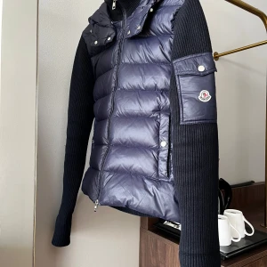 Mörkblå dunväst med stickade ärmar från Moncler - Snygg mörkblå dunväst från Moncler med stickade ärmar och huva. Västen har dragkedja framtill, tryckknappar och Moncler-logga på ärmen. Perfekt för lager-på-lager och ger en sportig look.