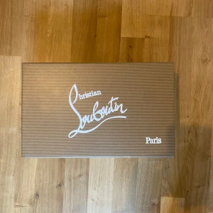 Svarta sneakers med nitar från Christian Louboutin - Säljer ett par svarta sneakers från Christian Louboutin med mattsvarta nitar på tån och klassisk röd sula. Skorna har snörning och är tillverkade i mocka. Kommer med originalpåse och låda.pris kan diskuteras 