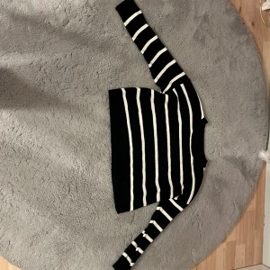 Svartvitrandig stickad tröja från SHEIN - Säljer en svart stickad tröja från SHEIN med vita horisontella ränder. Tröjan har lång ärm och rund halsringning. Perfekt för en stilren och enkel look.