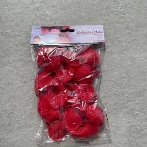 Röda konstgjorda rosenblad från Out of the Blue - En påse med 150 stycken röda konstgjorda rosenblad i tyg. Perfekta för dekoration eller sminkaccessoarer. Bladen har en naturlig form och tydlig struktur som liknar äkta rosenblad.