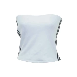 Vit adidas tubtopp med svarta ränder - Vit tubtopp från Adidas med svarta ränder längs sidorna och dragkedja på ena sidan. Den är axelbandslös och har en tight passform, perfekt till sommaren. Tunn gummiremsa längst upp på insidan som hjälper till att hålla toppen uppe!Superskön och i dunderskick 🙌🏼Adidasmärket sitter på baksidan, men toppen går att ha åt båda håll!