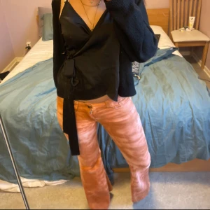 Orangea/rosa bootcut jeans - Säljer ett par orangea/rosa jeans med bootcut-passform. Byxorna har låg midja och klassiska fickor både fram och bak. Perfekta för dig som vill sticka ut med färg 