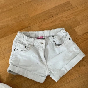 Vita jeansshorts från Pepperts - Snygga vita jeansshorts från Pepperts med klassisk femficksdesign och uppvikta benslut. Perfekta för varma dagar och enkla att matcha med allt. Stängs med knapp och dragkedja.