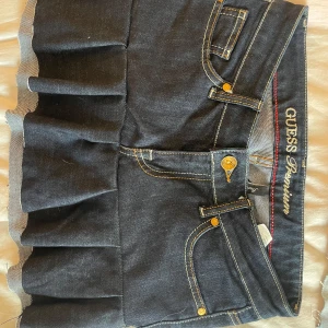 Egen sydd  jeanskjol med volang från Guess - Egensydd Supersnygg mörkblå jeanskjol från Guess med volang nertill och klassiska fickor fram och bak. Strl 27/S, KÖP EJ MELLAN 5juni-18juli, egensydd därav priset