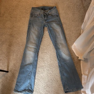 Ljusblå bootcut jeans från G-Star RAW - Säljer ett par ljusblå jeans från G-Star RAW med bootcut passform och klassiska fem fickor. Jeansen har en snygg tvätt och midwaist. Perfekta för dig som gillar en avslappnad men stilren look.