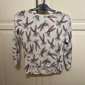 Grå långärmad tröja med Bugs Bunny från H&M - Säljer en grå långärmad tröja från H&M med ett tryck av Bugs Bunny över hela tröjan. Passar bra på folk som bär s o xs 