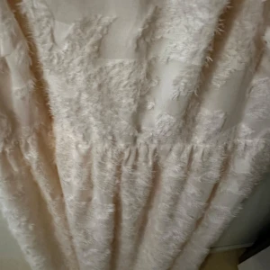 Ljus fluffig långklänning från Divided - Säljer en ljus långklänning från Divided med fluffig textur och volangdetaljer. Klänningen har korta puffärmar och knytning i ryggen. Perfekt för sommarens tillfällen när du vill sticka ut lite extra.