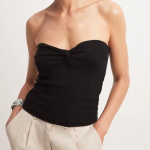 tubtopp med twistdetalj - Snygg svart axelbandslös tubtopp med twistdetalj framtill. Toppen är från Nakd i storlek S