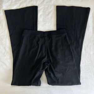 Svarta bootcut leggings från Gina Tricot - Svarta mid-waist leggings från Gina Tricot med bootcut-modell. Byxorna är tillverkade i ett stretchigt bomullsmaterial. I strl S