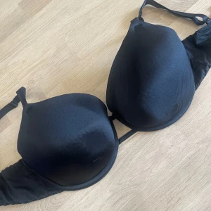 Svart BH från H&M - Svart BH från H&M med vadderade kupor och justerbara axelband. Klassisk modell med tre hyskor i ryggen för extra stöd. Perfekt för dig som vill ha en enkel och stilren BH i garderoben.