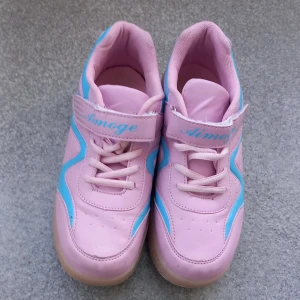 Rosa rullskor med blå detaljer - Säljer ett par inlines rosa med blå detaljer och inbyggda hjul i sulan som man kan gömma och gå som i vanliga skor. Skorna har snörning och kardborreband för extra stöd. Perfekta för dig som vill rulla fram med stil! Sulan  är mjukt vadderad. Storlek 37. 