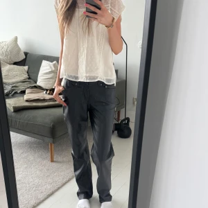 Svarta skinnbyxor med normal passform - Säljer ett par svarta skinnbyxor med raka ben och klassiska fickor fram och bak. Dem har en medelhög midja/ lite lägre. Byxorna har normal passform och stängs med dragkedja och knapp. Dem är uppsprättade längst ned men det syns knappt! Jag är 173 för referens💓 Midjemått: 33cm | Grenmått: 21cm | Innerbenslängd: 80cm