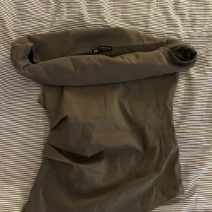 Olivgrön offshoulder topp från Zara - Trendig olivgrön offshoulder topp från Zara. Snygg och enkel design med tight passform, perfekt att matcha med kjol eller jeans. Mjuk och stretchig känsla i materialet för en bekväm look.