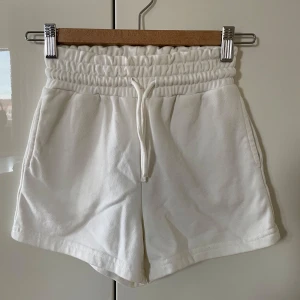 Vita shorts från Lindex Kids - Säljer ett par vita shorts från Lindex Kids i storlek 128. De är tillverkade i en mjuk blandning av bomull och polyester. Shortsen har en elastisk midja med snörning för justerbar passform.
