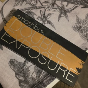 Ögonskuggspalett Double Exposure från Smashbox - Snygg ögonskuggspalett från Smashbox med 14 olika nyanser. Paletten innehåller både matta och skimrande färger, perfekt för att skapa olika looker. Inkluderar en smidig spegel och en dubbelsidig borste för enkel applicering.