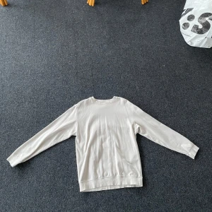 Vit tröja från H&M - Säljer en vit tröja från H&M i relaxed fit. Tröjan har långa ärmar och är perfekt för en avslappnad stil. Den är enkel och stilren, vilket gör den lätt att matcha med olika outfits.