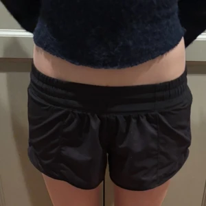 Svarta träningsshorts från Lululemon - Säljer ett par svarta träningsshorts från Lululemon. De är designade för att ge en bekväm passform med elastisk midja. Perfekta för gymmet eller löprundan.