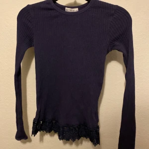 Mörkblå ribbad tröja med spetsdetalj - Snygg mörkblå ribbad tröja från WOW med långa ärmar och vacker spetsdetalj vid nederkanten. Perfekt för en stilren look. Är väldigt stor i storlek 