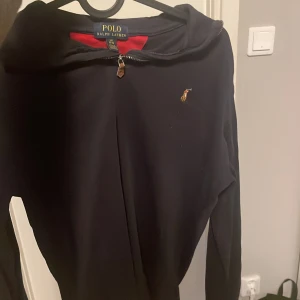 marinblå halvzip från Ralph Lauren - Säljer en stilren marinblå halvzip från Ralph Lauren med dragkedja och det klassiska broderade logotypen på bröstet. Perfekt för en avslappnad look. Passar bra till både jeans och joggers.