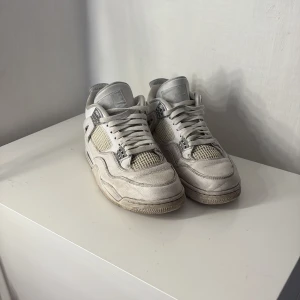 Vita Nike Air Jordans - Säljer ett par vita Nike Air Jordan 4 med klassisk design och snörning. Skorna har en stilren look med märkets logga på hälen och sulan. Perfekta för dig som älskar sneakers med en ikonisk stil. Priset kan diskuteras och förmodligen sänkas 