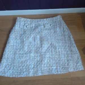 Champagne kjol i tweed - Snygg beige kjol från Lindex. Kjolen har en klassisk A-linjeform och är i ett tweed tyg