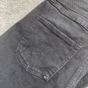 Svarta jeans med bootcut - Snygga svarta jeans med bootcut-stil och hög midja. De har en klassisk femficksdesign och stängs med dragkedja och knappar. Perfekta för en stilren look.