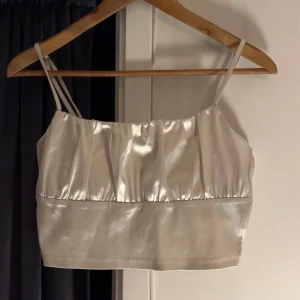 Vit satinlinne från H&M - Säljer en stilren vit satinlinne från H&M med smala axelband. Perfekt för en elegant look. Toppen har en glansig finish som ger en lyxig känsla. Passar bra till både jeans och kjol.💕