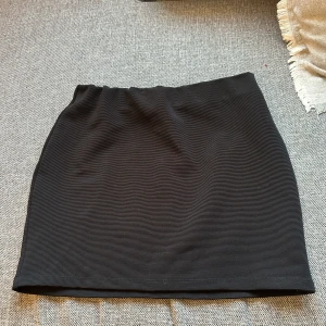 Svart kjol från Zara - Snygg svart kjol från Zara med en ribbad textur. Perfekt för en stilren look. Tillverkad i Turkiet och passar bra till olika tillfällen.