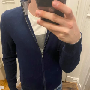 Mörkblå kofta från Pier One - Säljer en stilren mörkblå fullzip från Pier One med dragkedja framtill. Koftan har långa ärmar och en ribbad krage. (Dom vita prickarna är på spegeln och inte på tröjan)Modellen är ca 182, tveka inte att kontakta vid eventuella frågor 😀