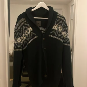 Svart stickad kofta/cardigan  med mönster - Säljer en tvär stilig svart kofta/cardigan med svarta mönster. Storlek S perfekt för våren. Tröjan visar tecken på användning men inga stora defekter. Om de är några funderingar eller frågor är de bara att skriva. 