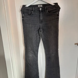 Grå bootcut jeans från ONLY - Säljer ett par grå jeans från ONLY i bootcut-modell. Jeansen har fem fickor, normal passform och råa, fransiga benslut för en cool look. Perfekta till vardags och lätta att matcha med olika toppar.