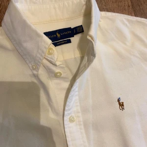 Vit skjorta från Ralph Lauren - Klassisk vit skjorta från Ralph Lauren med broderad logga på bröstet. Perfekt nu inför sommaren, skjortan är i nyskick och används ett fåtal gånger. Den är S och passar sin storlek, speciellt mellan 170-180.