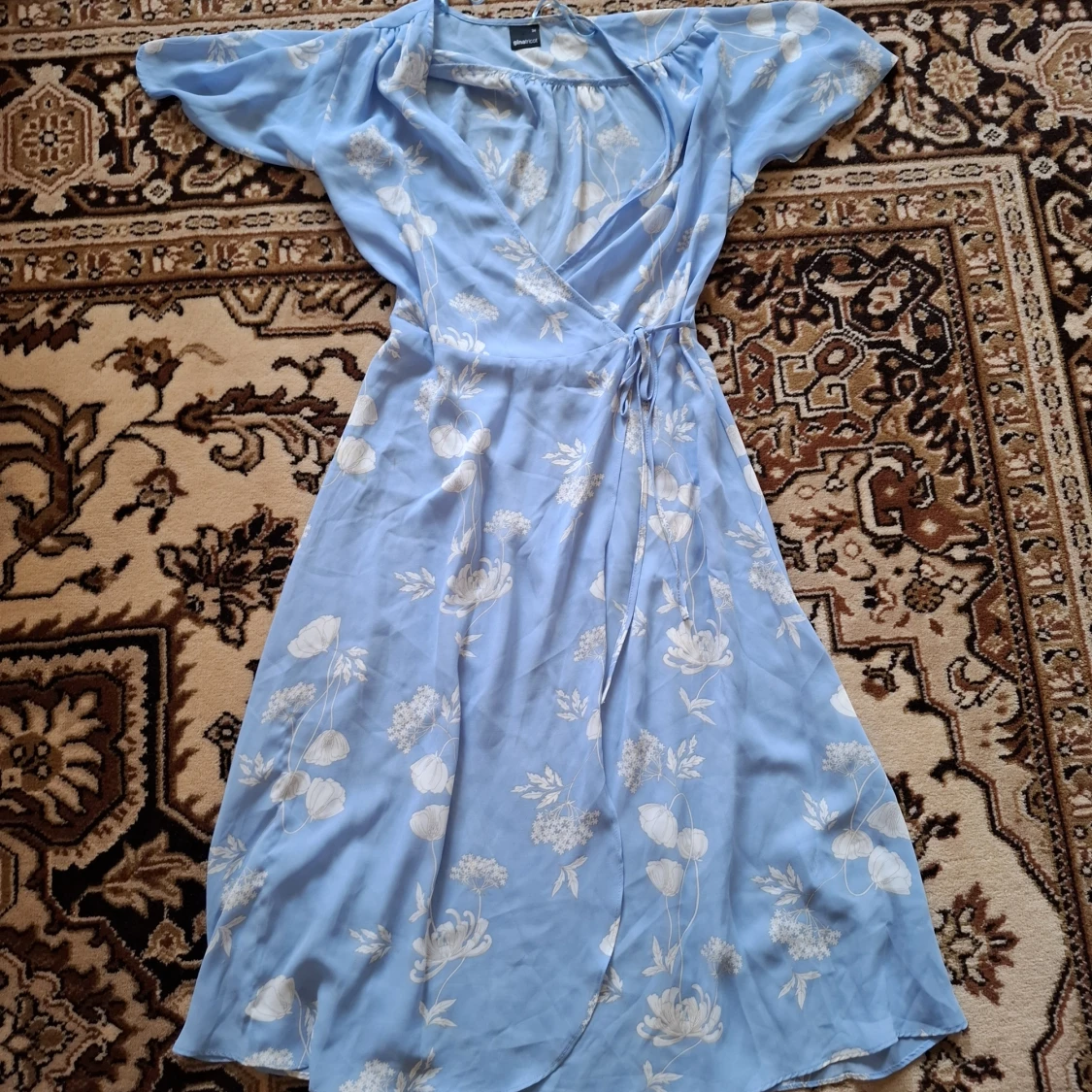 Ljusblå blommig omlottklänning