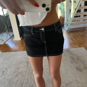 Svart minikjol med vita sömmar - Svart minikjol med markerade vita sömmar.