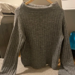 Grå ribbstickad tröja - Mysig grå ribbstickad tröja med lång ärm och rak passform. Tröjan har en bredare halsringning och är perfekt för kyligare dagar. Enkel och stilren design som passar till det mesta. Pris kan diskuteras.