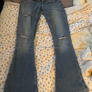 Blå bootcut jeans från Gina Tricot - Säljer ett par blå bootcut jeans från Gina Tricot i storlek S. Jeansen har slitna detaljer på benen och klassisk femficksdesign. Nypris: 360. Finns ej i lager 