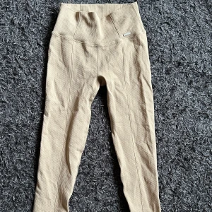 Beige leggings från Aim'n - Säljer ett par beige leggings från Aim'n med hög midja och ribbad struktur. Byxorna är stretchiga och tillverkade i ett mjukt material som passar perfekt till träning eller en aktiv vardag.