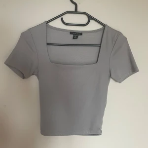 Ljusgrå croppad topp från Amisu - Säljer en ljusgrå croppad topp från Amisu med fyrkantig ringning och korta ärmar. Enkel och stilren design som passar perfekt till jeans eller kjol. Supermjuk och skön att bära.🤍