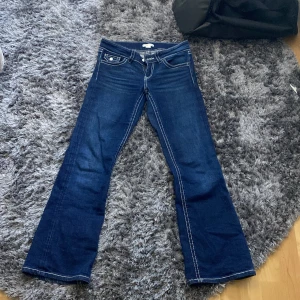 Mörkblå bootcut jeans från Gina Tricot - Mörkblå jeans från Gina Tricot i bootcut-modell med vita kontrastsömmar och klassiska fickor både fram och bak.