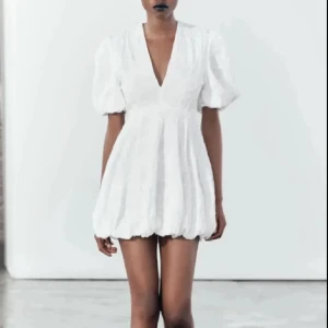 Vit zara klänning - Superfin vit kortklänning med puffärmar och v-ringning. Klänningen har en ballongformad kjol och markerad midja som ger en söt och trendig siluett. Perfekt till student eller sommarens alla tillfällen.